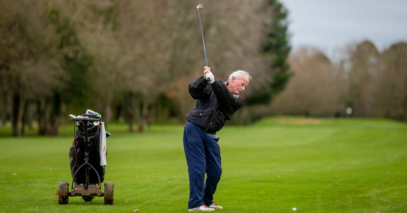 The man is standing on the grass with a stick in his hands